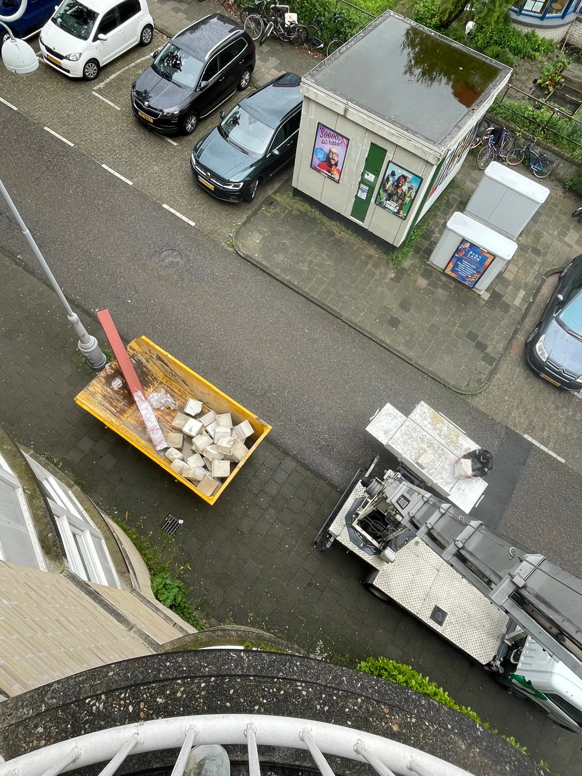 Ladderlift en container op straat, gezien vanaf de verdieping